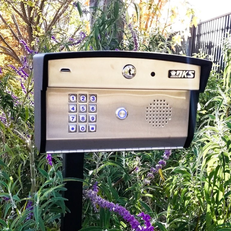 DoorKing callbox with illuminated call button at a gated property entrance